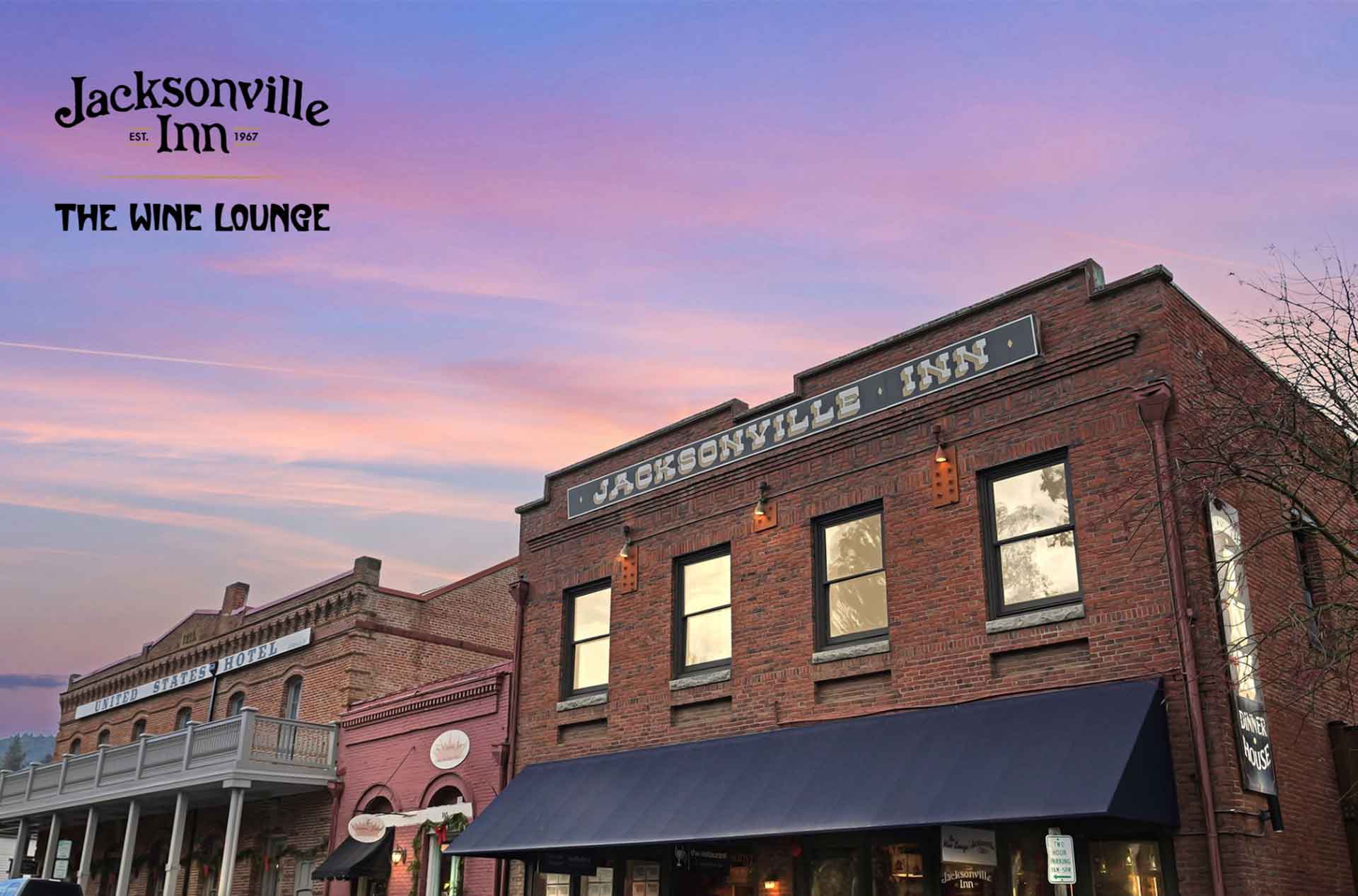 Jacksonville Inn with a pink and purple sky backdrop. The building features a sign reading "JACKSONVILLE INN" and "THE WINE LOUNGE" below. It is a brick structure with large windows and a dark awning.
