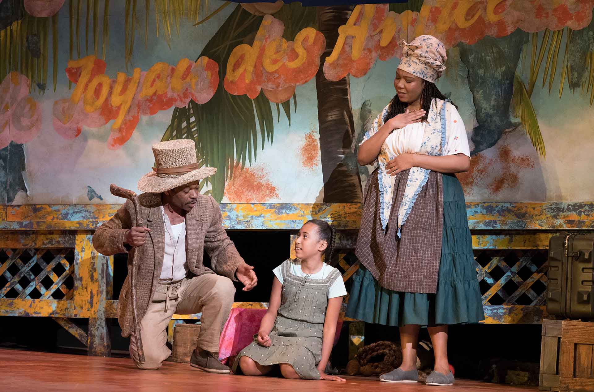 A person kneeling with a child, another person standing to the side with their hand over their heart.