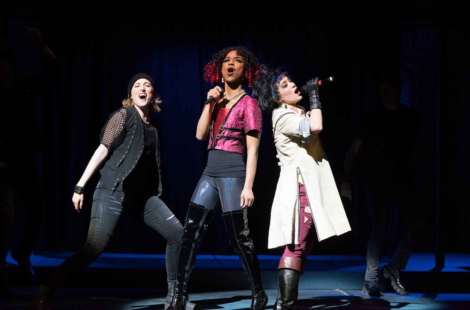 Three people in rock-and-roll costumes singing.