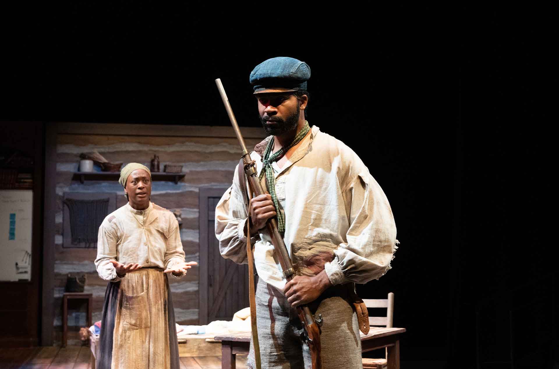 Person standing behind another person holding a rifle.