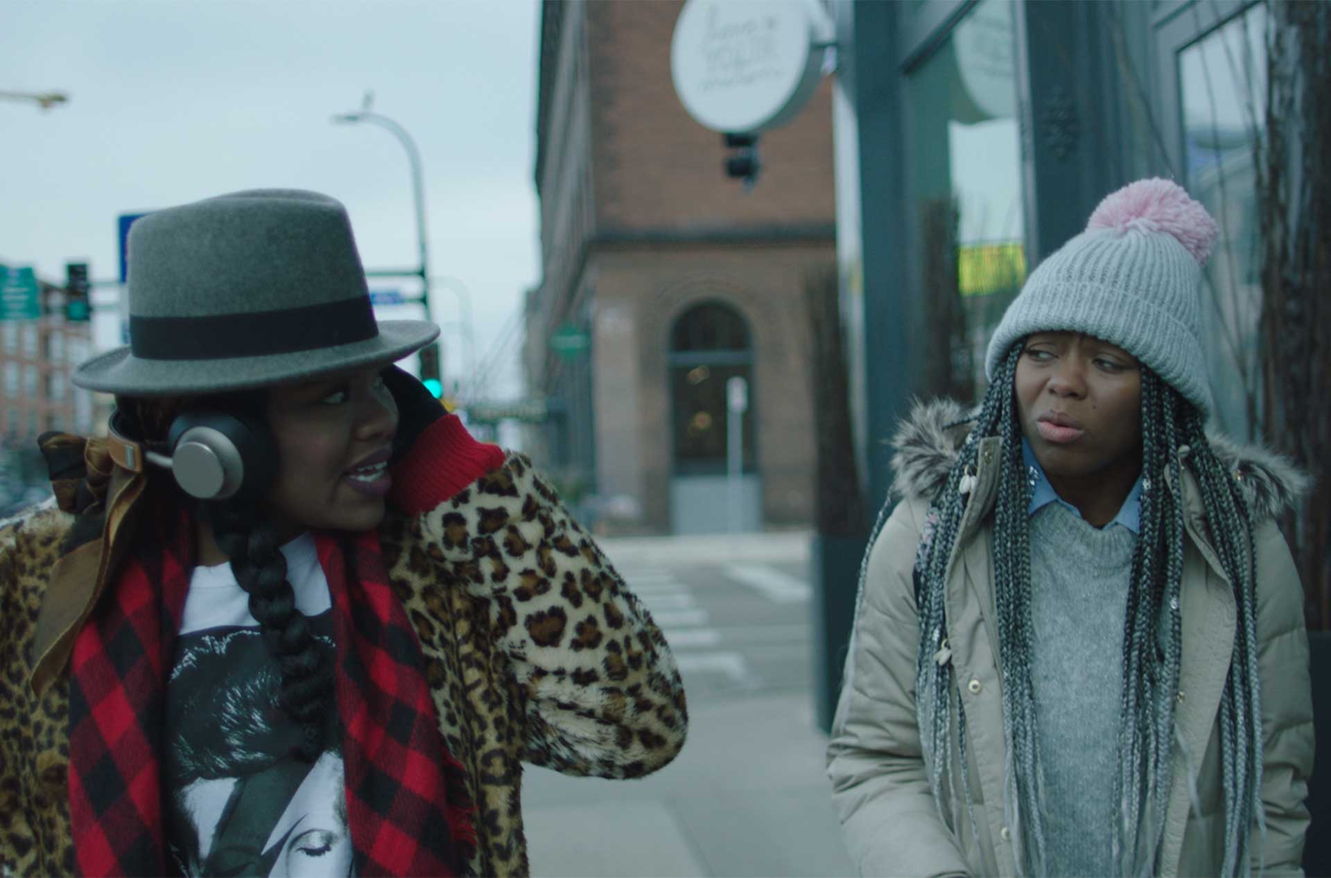 Two people walking down a sidewalk and talking.