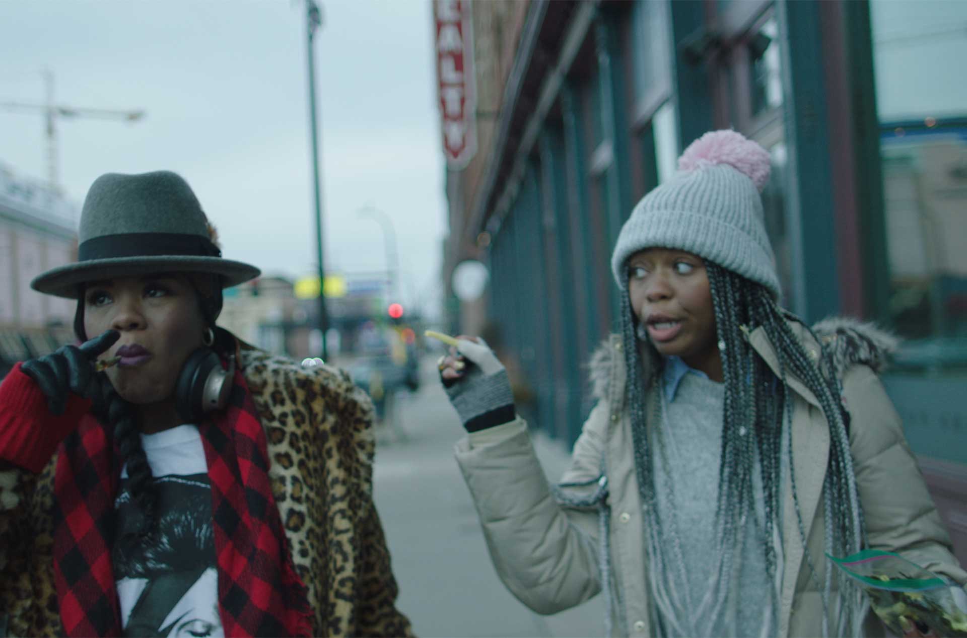 Two people walking down a sidewalk and talking.