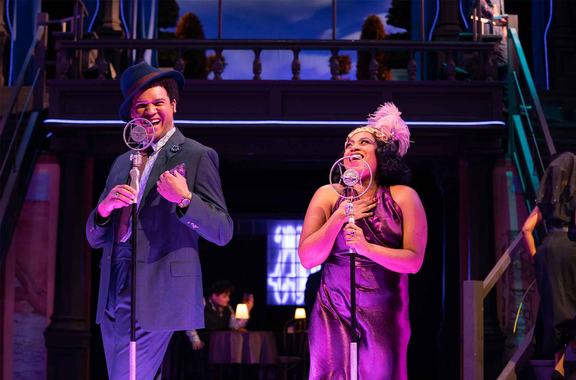 Two people on stage singing into microphones.