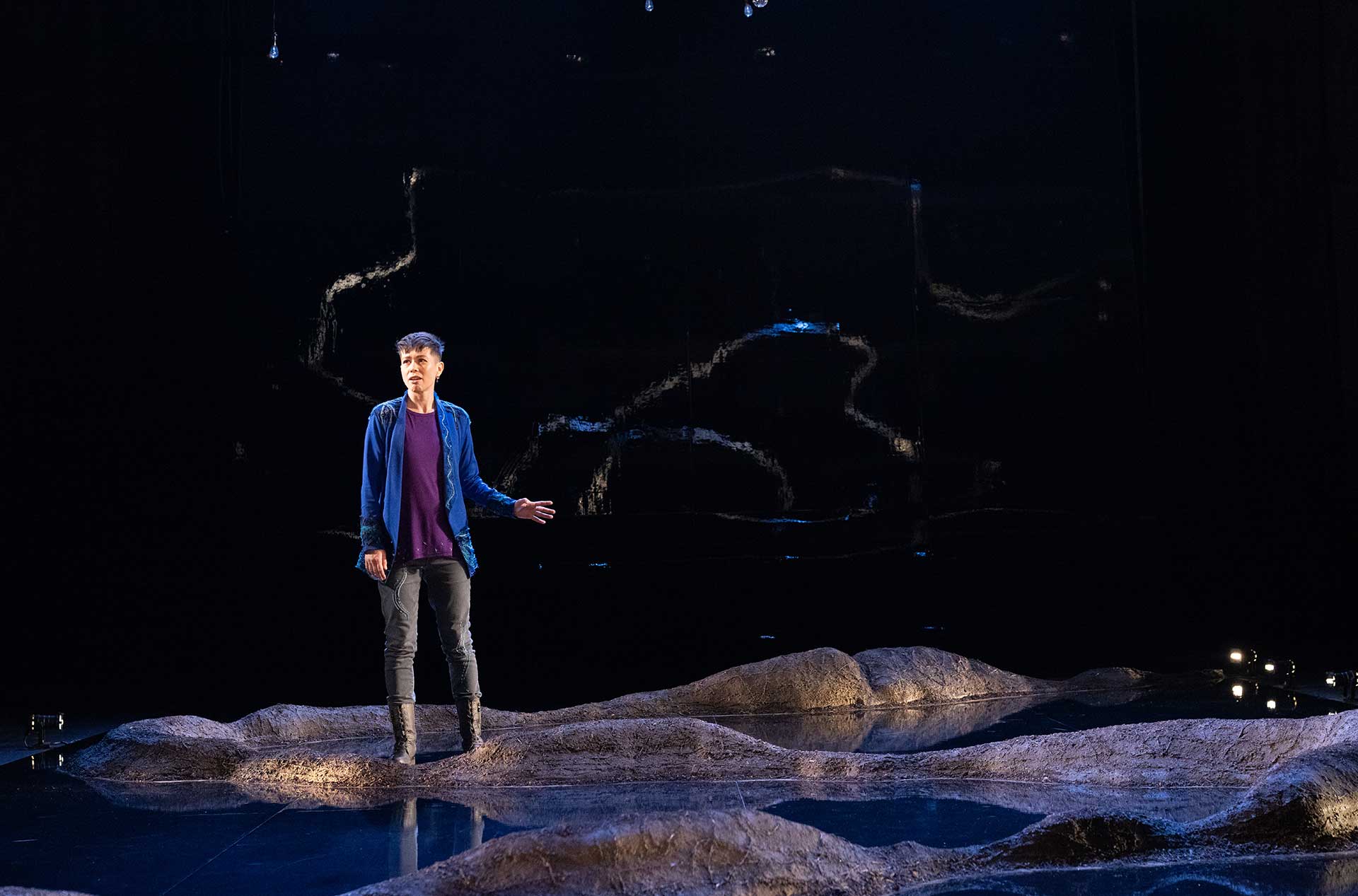 A person standing on the stage looking out toward the audience. 