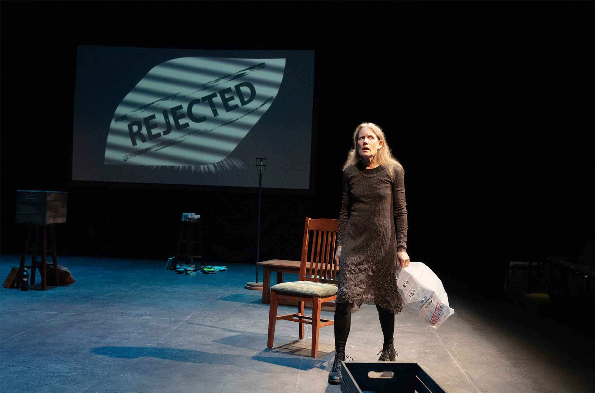 A woman standing holding a rejection letter.