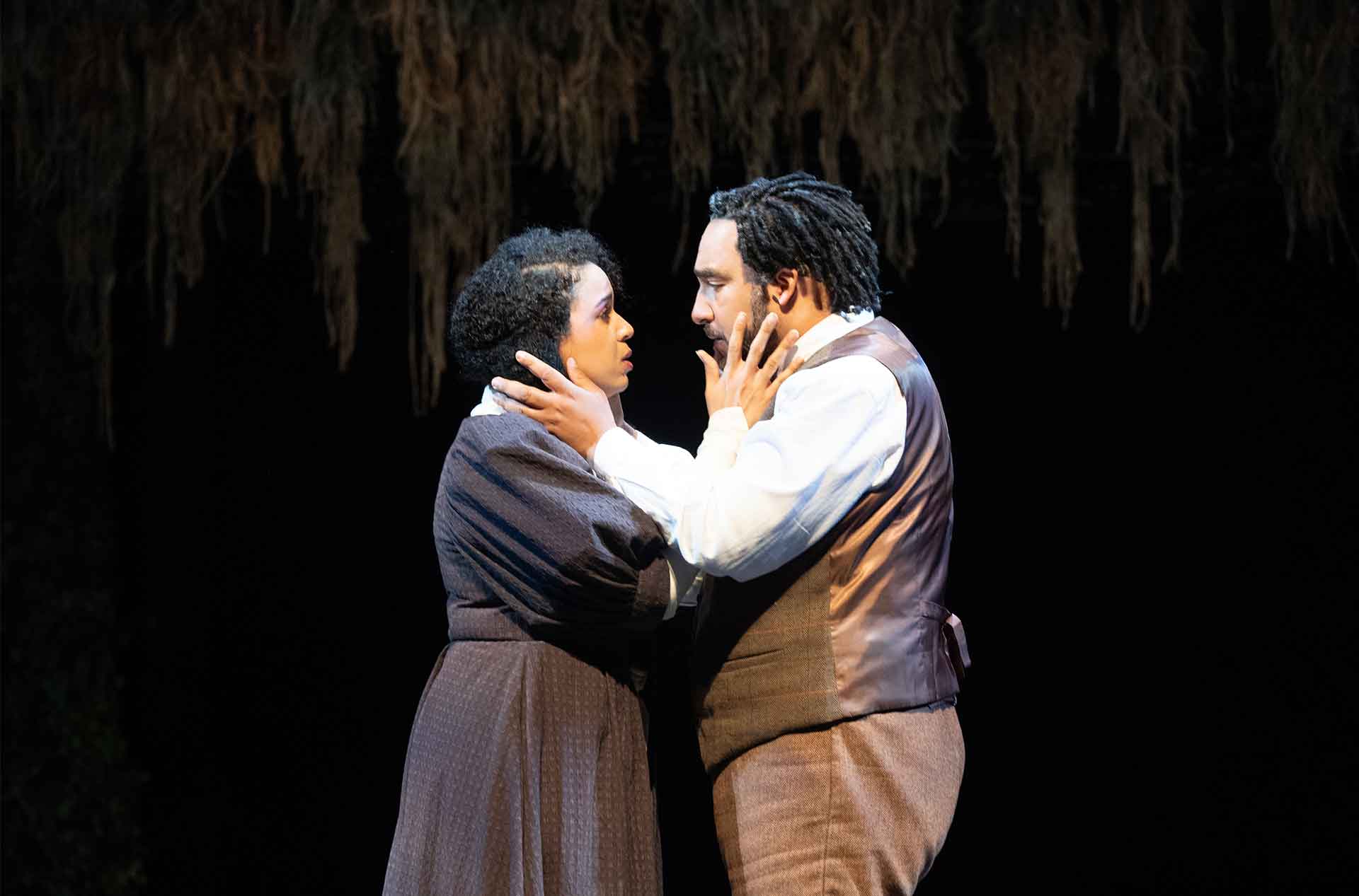 Two people looking into each others eyes holding the others face.