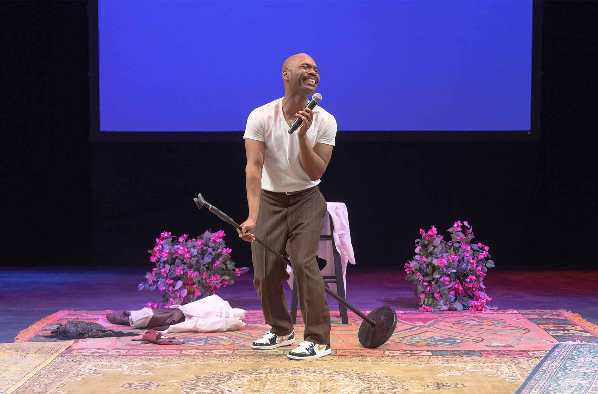 A person standing holding a microphone stand in one hand and the microphone in the other.