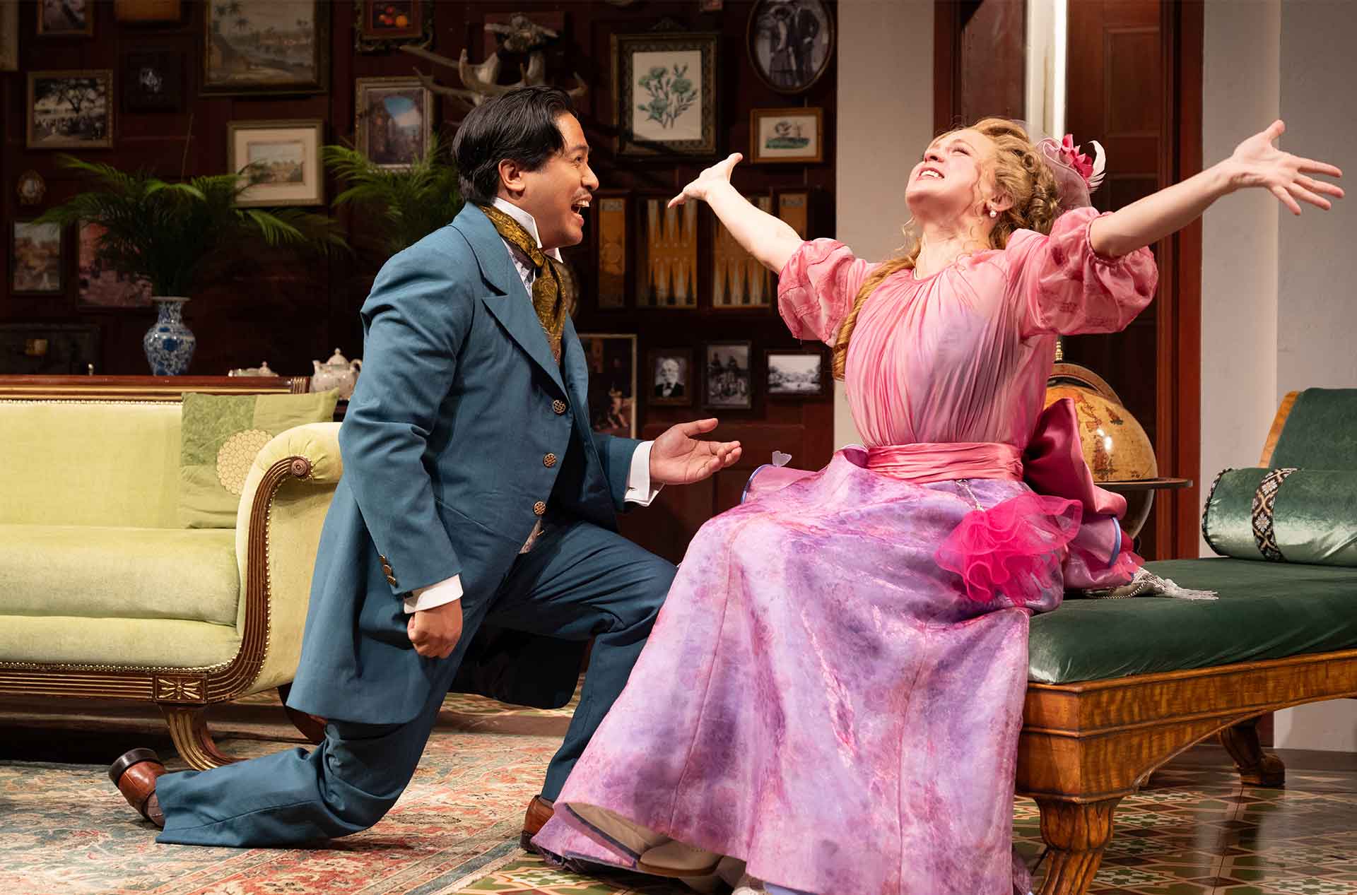 One figure kneels in front of another who throws their arms in the air in apparent joy, both dressed in elaborate period clothing.