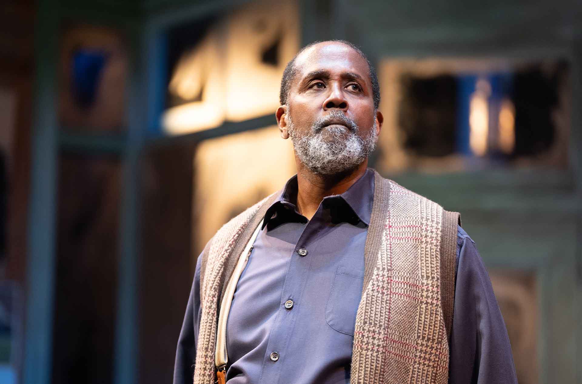 A person with a thoughtful and determined expression is illuminated under dramatic stage lighting