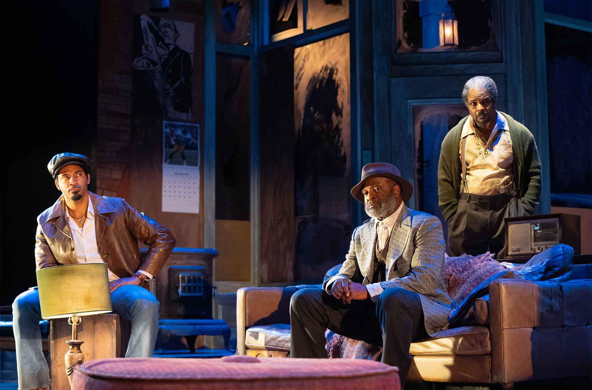 Three people are gathered in a dimly lit room with warm, dramatic lighting.