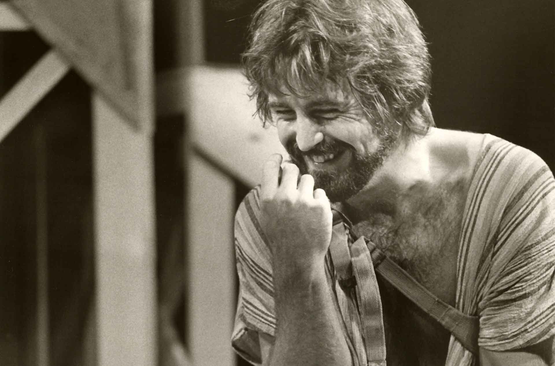 Person holding hand up in front of their face and smiling.