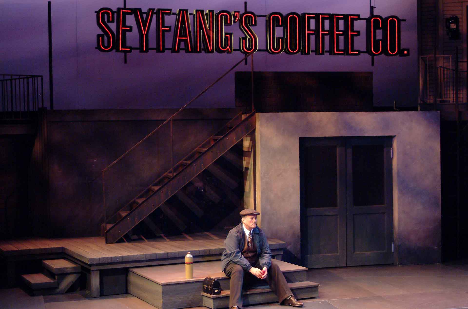 Person sitting alone under a coffee company sign.