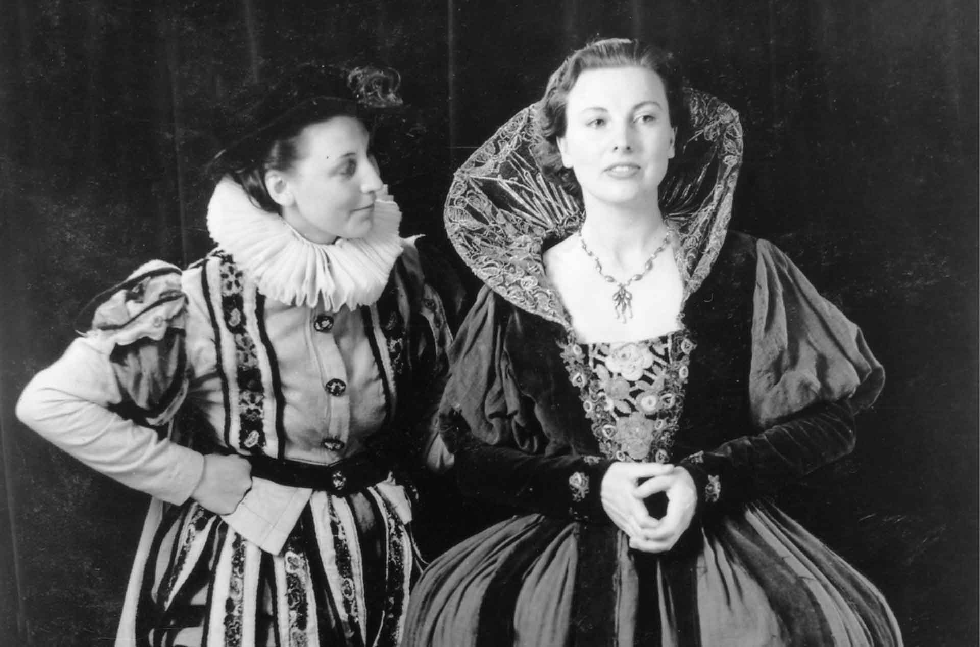 Two people in old fashioned outfits standing close to each other.