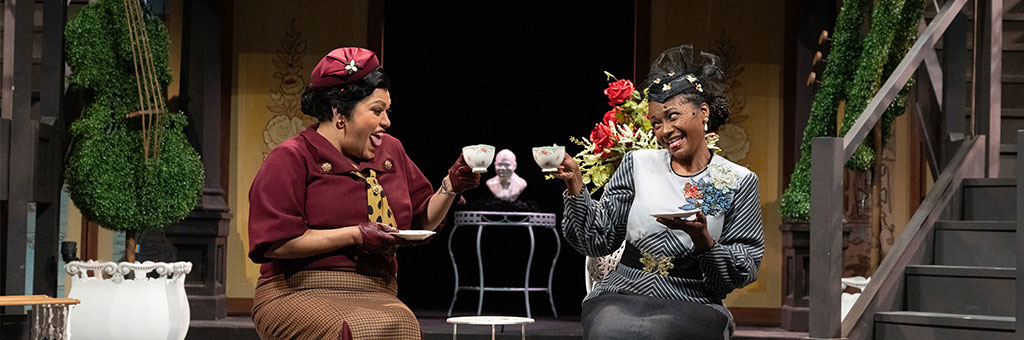 Two people chatting and having tea at a table.