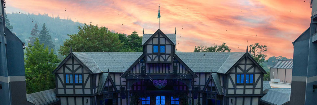 Tudor-style theater exterior at sunset with glowing sky.